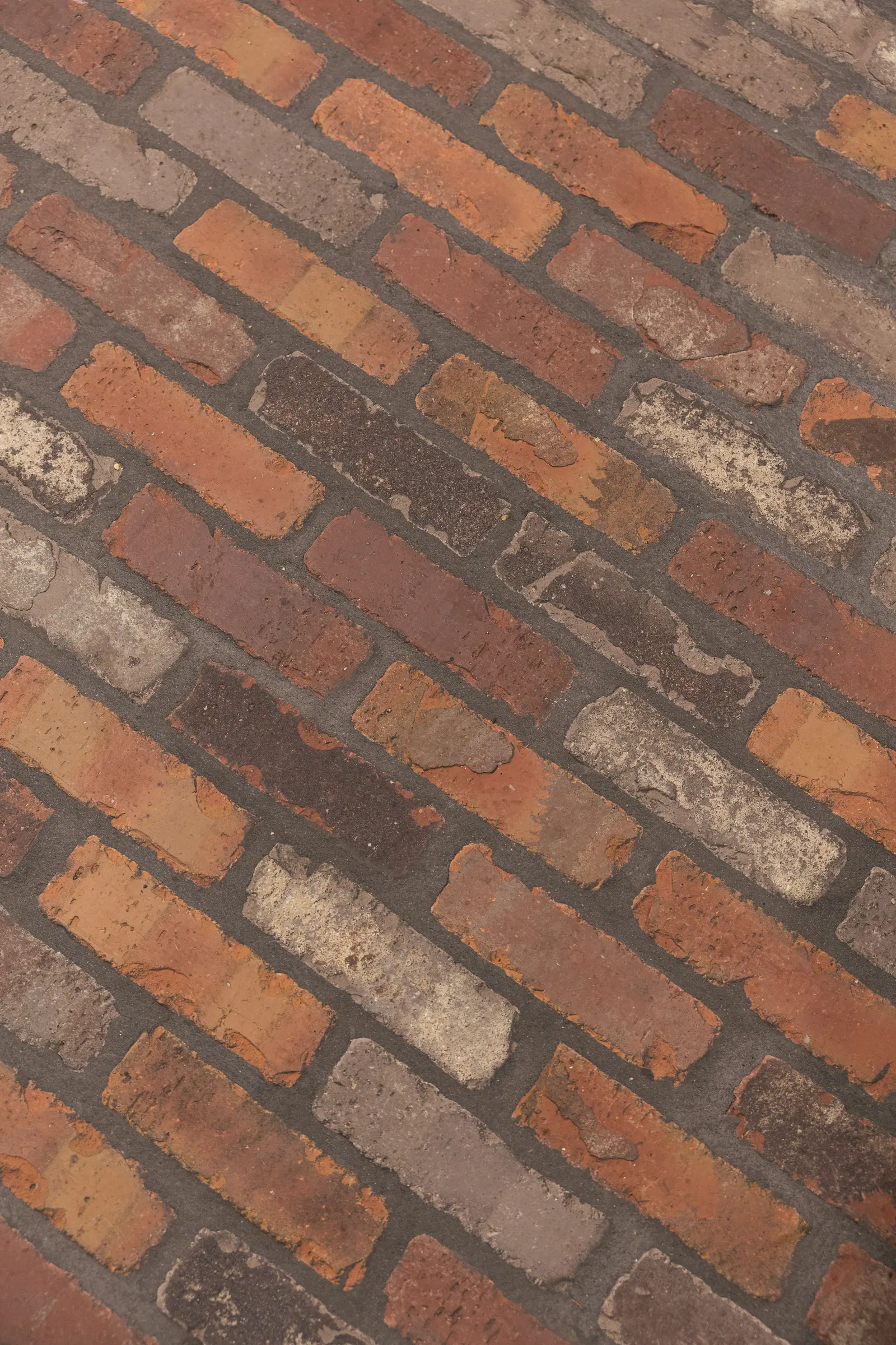 Close-up of the sealed thin brick floor laid in a running pattern.