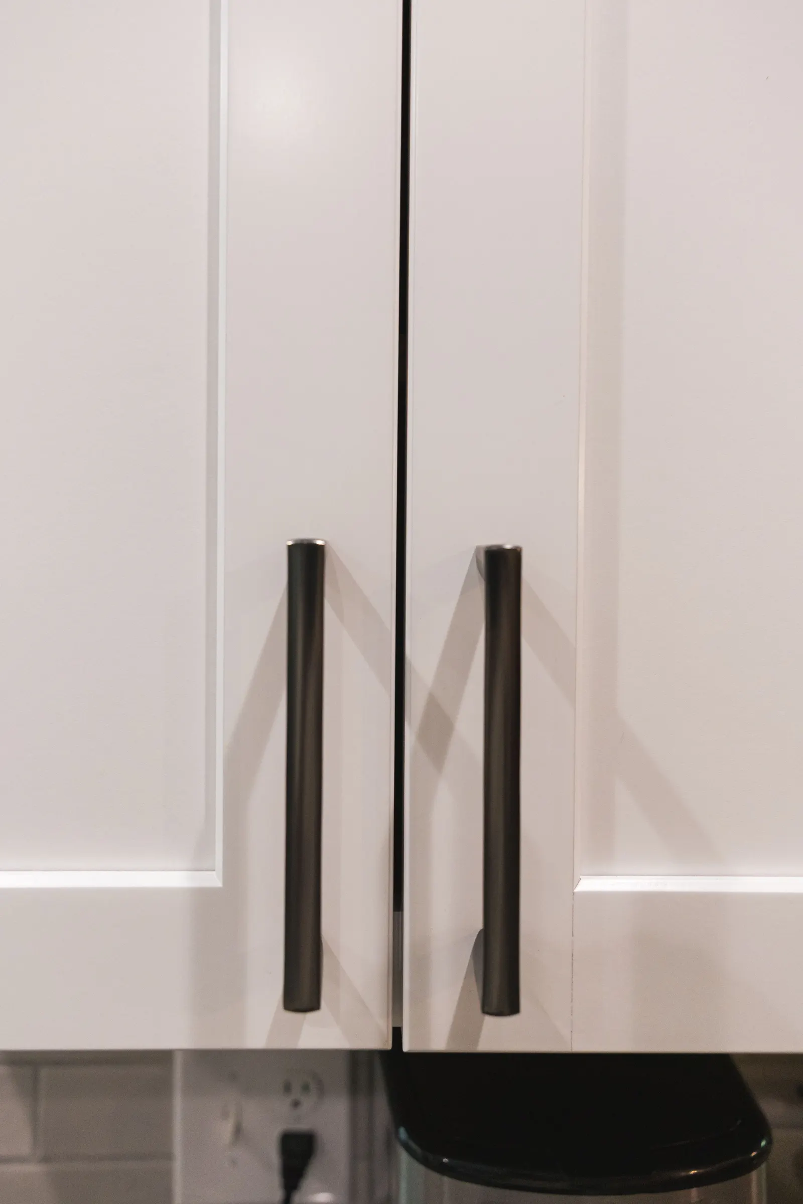 White shaker cabinet doors with long black pulls.
