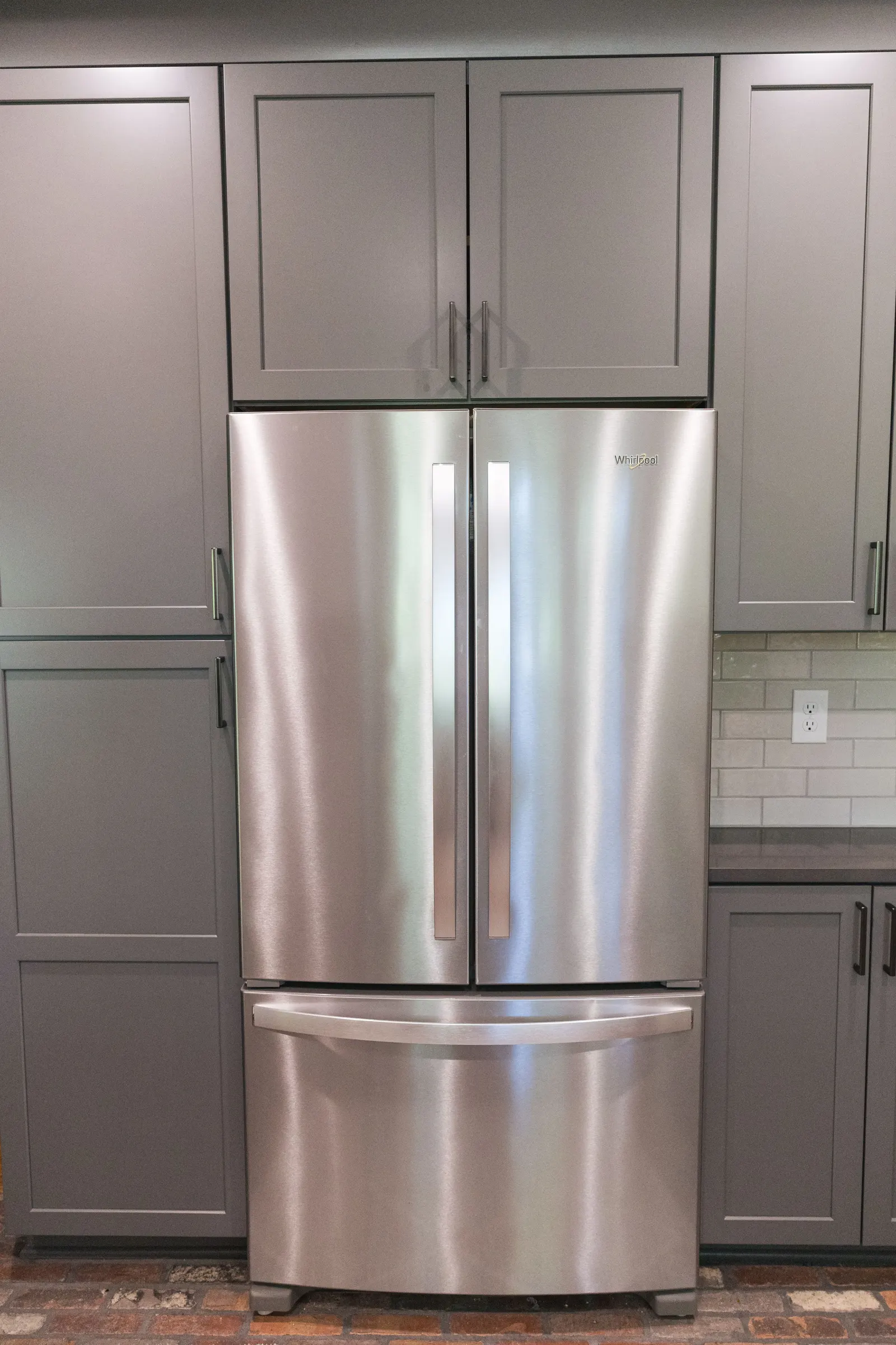 The refrigerator built into the gray pantry wall.