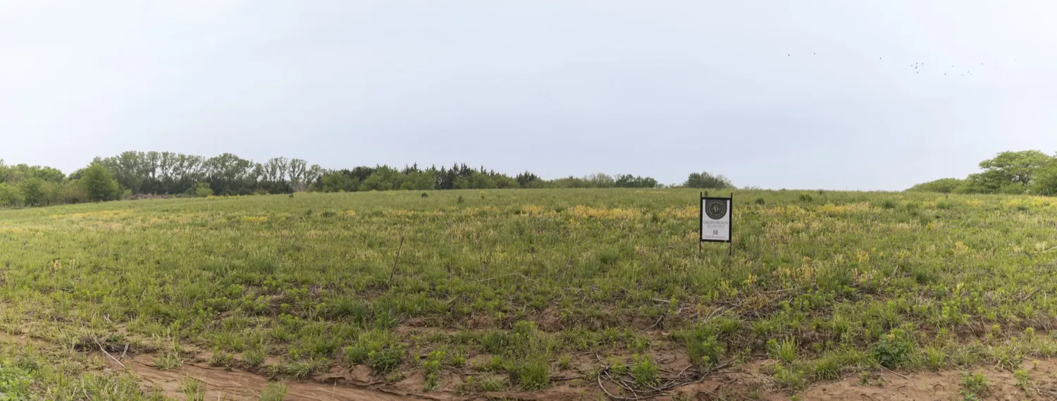 Wide view of the Liv Hus land and treeline at Bluestem Lake